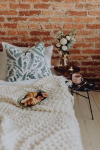 Kaboompics - Vertical Bedroom Breakfast Still Life with Croissants, Figs and Pink Coffee Cup beside White Floral Bouquet