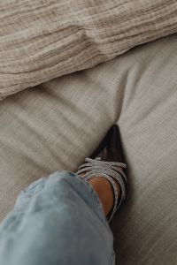 Kaboompics - Black Rhinestone Pumps and Blue Jeans on Soft Neutral Bedding