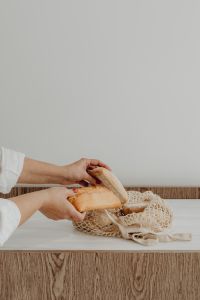Kaboompics - Hands Placing Fresh Ciabatta and Baguette into a Mesh Bag