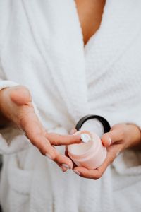 Kaboompics - Vertical Beauty Close-Up of Moisturizer on a Fingertip and Open Cosmetic Jar