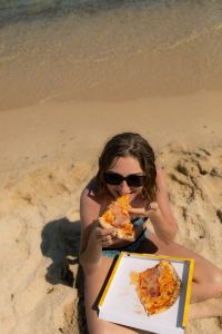Kaboompics - Overhead View of a Woman Eating Pizza on the Beach