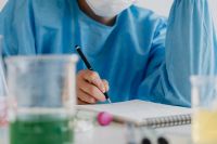Kaboompics - Scientist Writing Notes Beside Laboratory Glassware