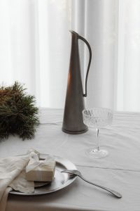 Kaboompics - White Wrapped Christmas Gift on Silver Plate with Crystal Coupe and Evergreen Wreath
