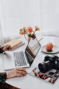 Kaboompics - Woman Working on a Laptop with a DSLR Camera and Notebook