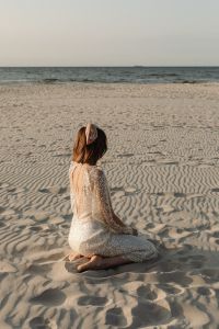 Kaboompics - Solitary Faceless Woman Sitting on Rippling Beach Sand