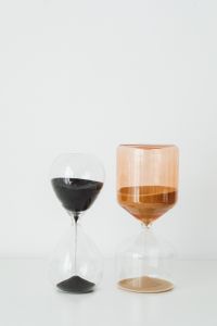 Kaboompics - Vertical Still Life of Black and Amber Glass Hourglasses with Ample White Copy Space Above