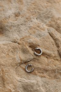 Kaboompics - Silver Hoop Earrings on Natural Limestone Texture