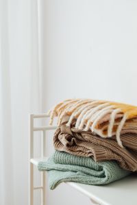 Kaboompics - Stack of Folded Pastel Sweaters on a White Shelf