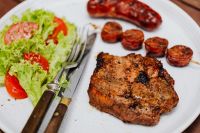 Kaboompics - Grilled Pork Neck Steak with Sausage Skewers and Fresh Salad, Rustic Barbecue Meal