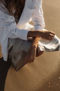 Kaboompics - Faceless Woman Sitting on Beach in White Shirt and Satin Skirt