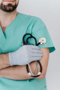 Kaboompics - Gloved Hand Holding a Stethoscope on Mint Scrubs, Close-Up Clinical Care Detail
