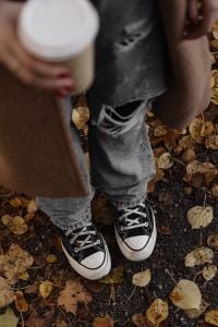 Kaboompics - Black Sneakers and Ripped Jeans Among Fallen Autumn Leaves