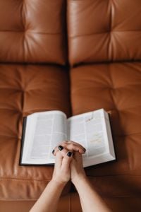 Kaboompics - Prayer Hands and Open Bible on a Brown Leather Sofa with Copy Space