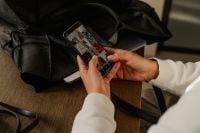 Kaboompics - Female Hands Reviewing Photos on Smartphone Beside Laptop