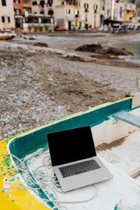 Kaboompics - MacBook on a Yellow Dinghy Below a Coastal Village