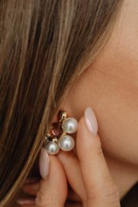 Kaboompics - Pearl Cluster Drop Earrings with Gold Settings, Close-Up of a Woman Adjusting Statement Jewelry