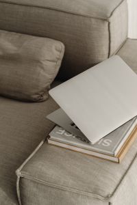 Kaboompics - Silver Laptop on Stacked Books on a Neutral Sofa, Home Office Detail