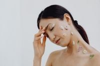 Kaboompics - Eyes-Closed Asian Beauty Portrait with Floral Face Accents and Hand at Temple