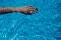 Kaboompics - Woman's Hand Floating Across Sunlit Blue Pool Water, Close-Up Summer Swimming Lifestyle