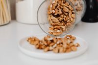 Kaboompics - Walnuts Spilling from a Glass Jar onto a White Plate, Healthy Pantry Still Life
