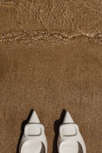 Kaboompics - White Pointed-Toe Heels on Sandy Shore with Negative Space