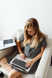 Kaboompics - Female Student Studying on Armchair with Laptop and Notebook