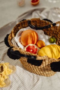 Kaboompics - Wicker Beach Basket with Citrus Fruit on a Striped Towel