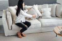 Kaboompics - Woman Adjusting Sofa Pillows in a Minimal Living Room