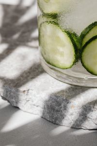 Kaboompics - Close-Up Cucumber Slices in Chilled Detox Water on a Marble Block, Condensation and Soft Natural Shadows