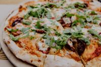 Kaboompics - Restaurant Pizza on a Wooden Board with Soft-Focus Decor