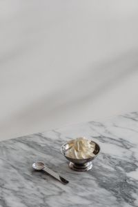 Kaboompics - Whipped Cream Dessert in a Silver Pedestal Bowl with Spoon, Minimal Marble Table Food Still Life