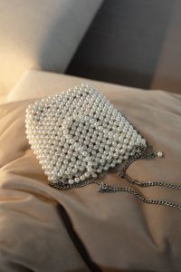 Kaboompics - Pearl Beaded Clutch Bag with Chain on Soft Beige Fabric