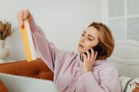 Kaboompics - Woman on a Phone Call Holding an Orange Notebook