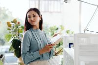 Kaboompics - Portrait of Asian Woman Holding a White Notebook in a Bright Office