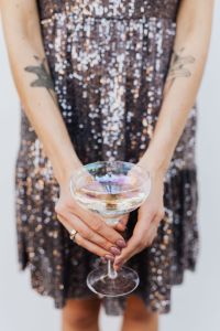 Kaboompics - Tattooed Arms Framing a Champagne Coupe over Sequin Dress