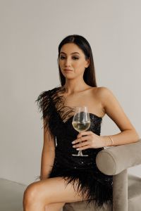 Kaboompics - Seated Woman Facing Camera with Wine Glass in Black Feather-Trimmed Dress