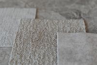 Kaboompics - Layered Neutral Bouclé Upholstery Fabric Swatches on Stone