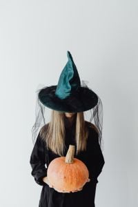 Kaboompics - Woman in Witch Costume Holding a Large Orange Pumpkin
