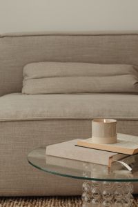 Kaboompics - Candle and Open Book on Glass Table against Neutral Sofa