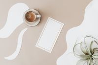 Kaboompics - Cappuccino and Blank Gold-Trimmed Card on Beige Abstract Table beside Air Plant