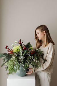 Kaboompics - Woman Behind Lush Christmas Greenery Arrangement