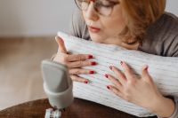 Kaboompics - Woman Stroking a White Ribbed Pillow beside Microphone for Relaxing ASMR