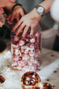 Kaboompics - Hand Arranging Christmas Baubles in a Clear Decorative Container