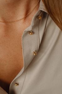 Kaboompics - Gold Necklace on Woman's Chest with Tan Silk Shirt