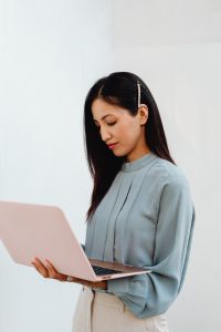 Kaboompics - Asian Woman Holding a Pink Laptop Against a White Background