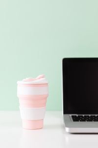 Kaboompics - Pink Collapsible Travel Mug with Laptop and Mint Green Copy Space