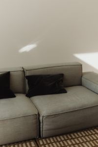 Kaboompics - Minimalist grey modular sofa with black velvet pillows and sunlight
