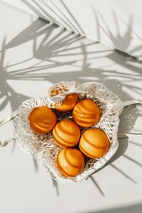 Kaboompics - Overhead Reusable Net Bag of Oranges on White with Palm Shadows