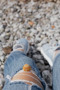 Kaboompics - Blurred Legs on a Pebble Beach with Seashell in Foreground