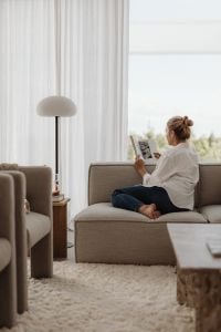 Kaboompics - Woman Reading a Magazine on a Neutral Sofa by the Window